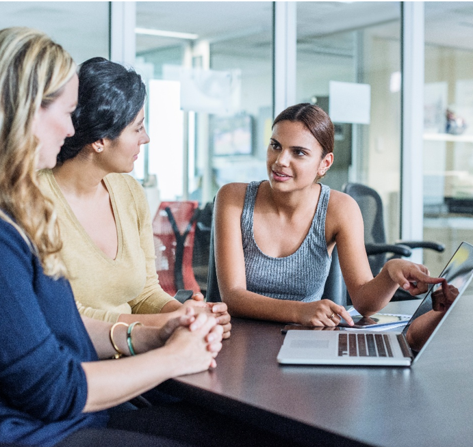 Three office workers looking at laptop