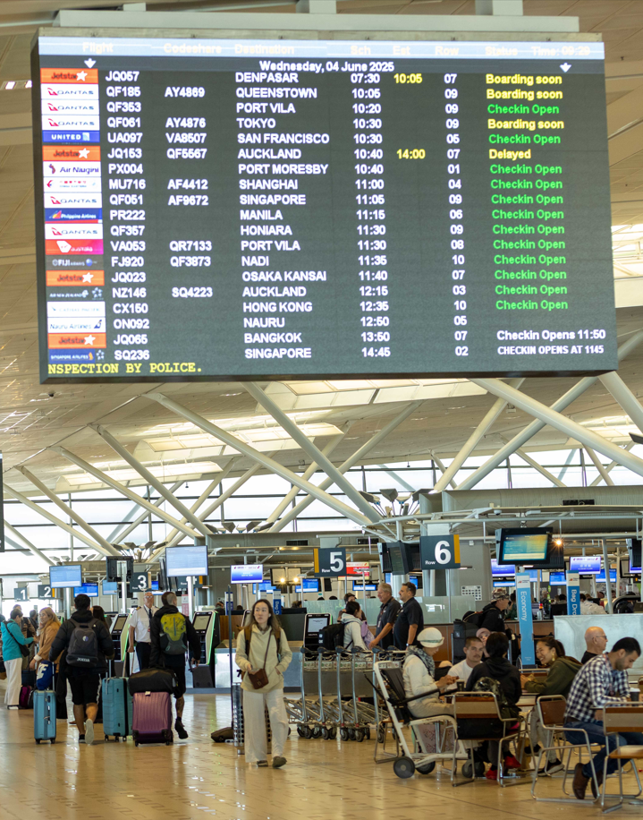 departures board and crowd at international airport terminal