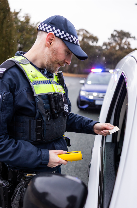 policeman standing next to vehicle checking licence