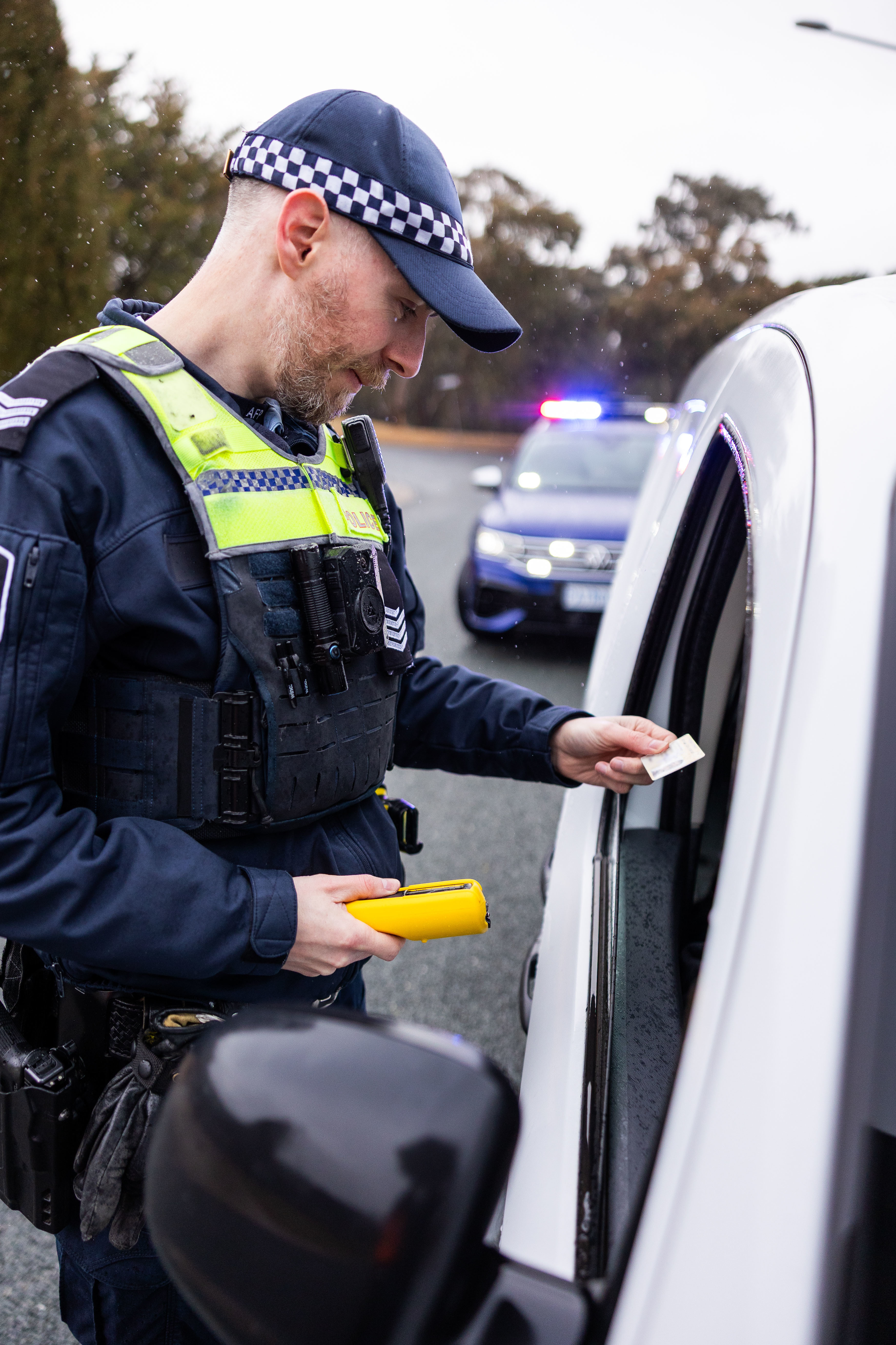 policeman standing next to a car checking a licence 