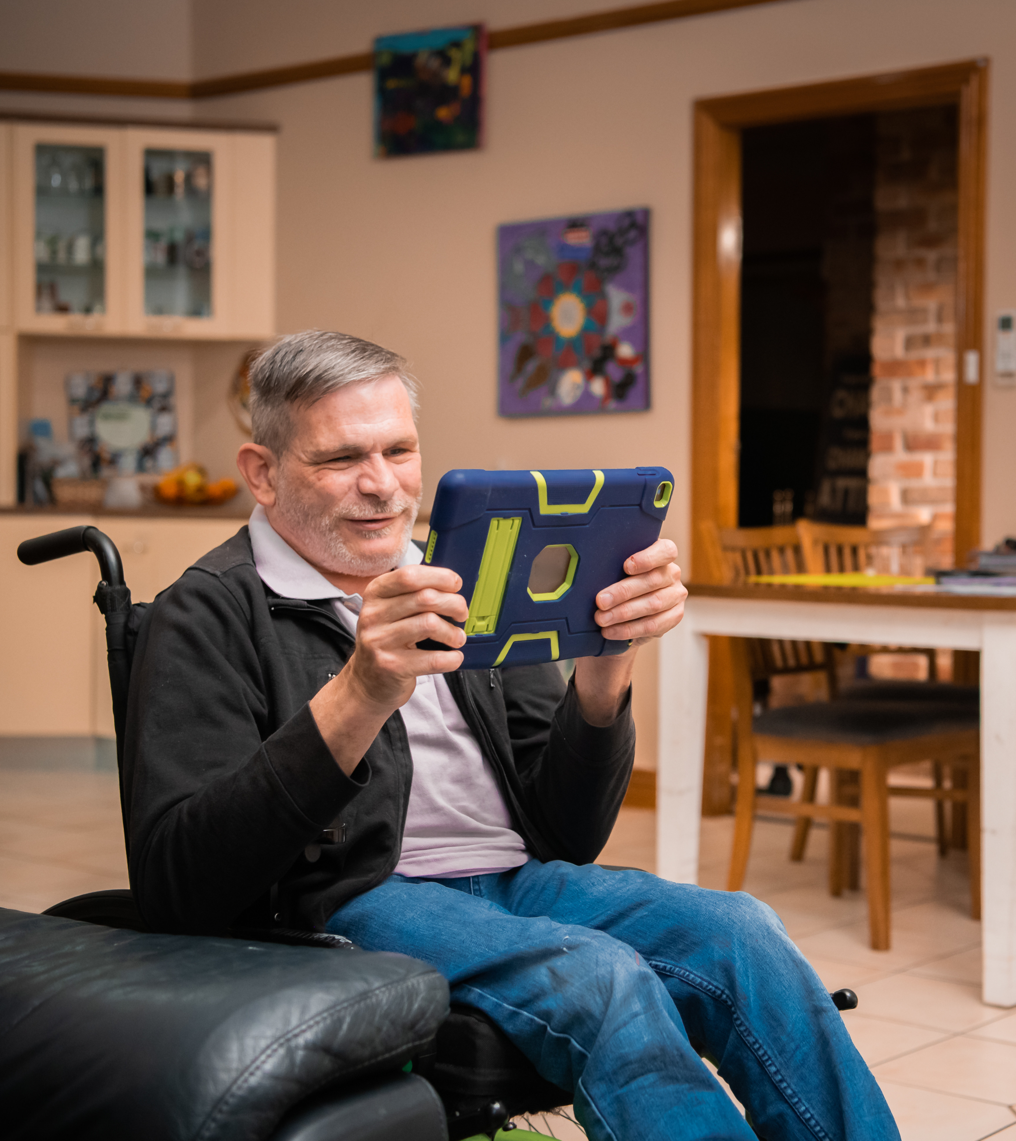 older man in wheelchair looking at something on a tablet