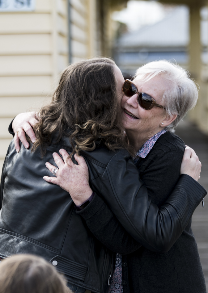 women in black hugging outside country hall