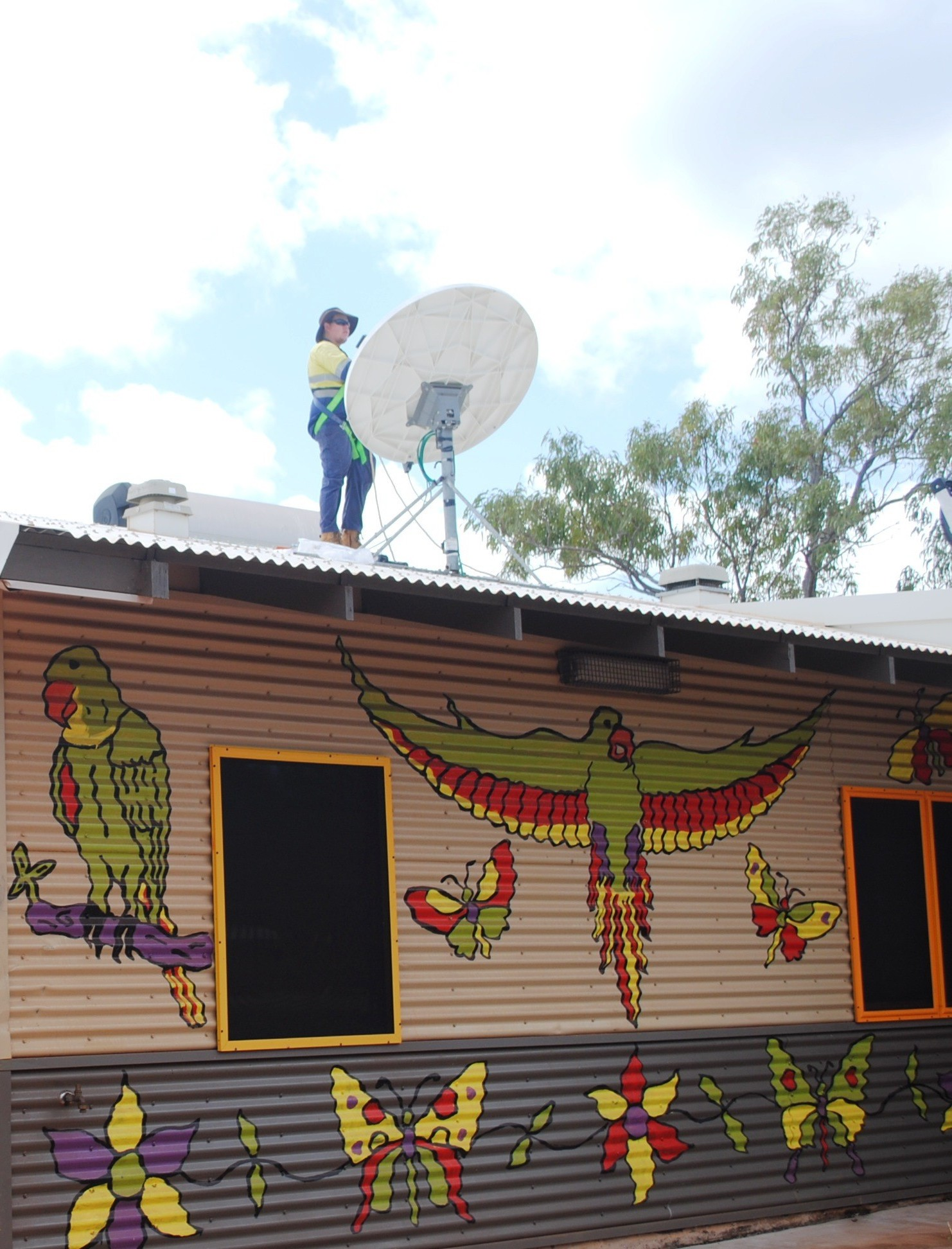 worker on roof of school with satellite dish